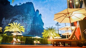 Ein Resort mit Außenbestuhlung, Palmen und einem Bergpanorama.