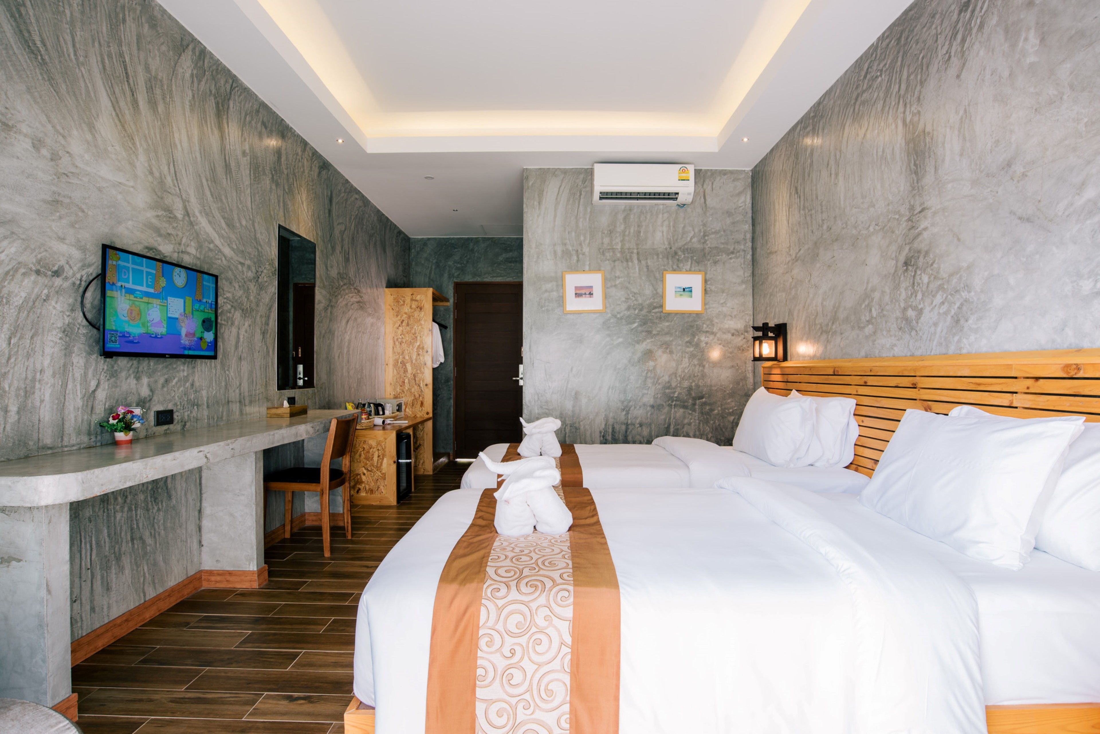 Habitación de hotel con una cama grande, cabecera de madera, un escritorio con silla, televisor y cuadros en la pared.