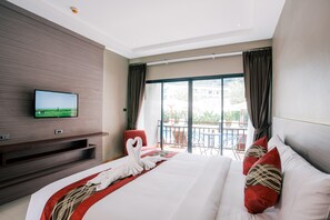 A hotel room with a large bed, a flat-screen TV mounted on the wall, a balcony with outdoor furniture, and a view of the cityscape. - Frank Ao Nang Krabi Resort (Krabi)