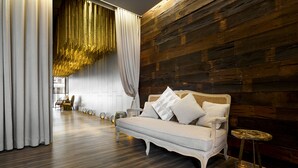 A modern room with a wooden wall, a white sofa with decorative pillows, and a small round table with a candle. - Pod Labo (Hualien City)