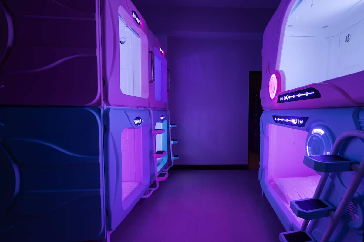 Une rangée de fauteuils de massage équipés de panneaux de commande, éclairés par une lumière violette.