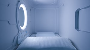 A room with a bed, a control panel, and a circular window. - Pod Labo (Hualien City)