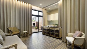 A spacious living room with a sofa, armchairs, a small table, and a cabinet with drawers. - Pod Labo (Hualien City)