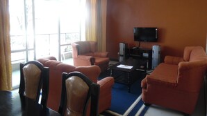 Una sala de estar con un ventanal grande, un televisor de pantalla plana y una mesa de centro.