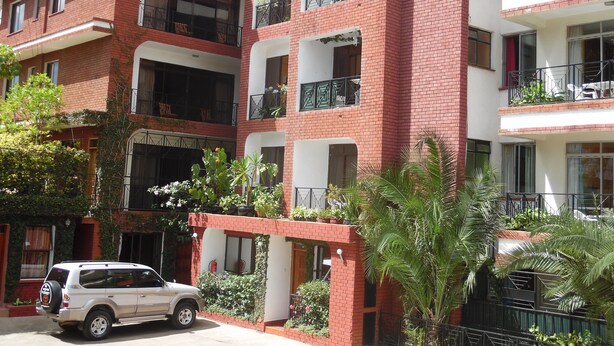 Un edificio de varios pisos con fachada de ladrillo, balcones con barandillas de metal y plantas en macetas.