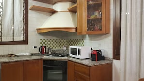 A kitchen with a stove, microwave, kettle, and cabinets. - Venetian Style (Venice)