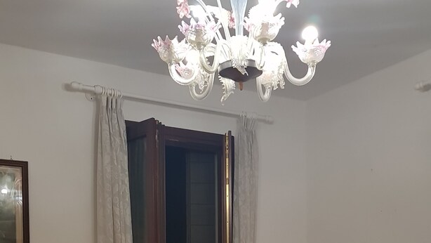 A room with two beds, a chandelier, a door, and a radiator. - Venetian Style (Venice)