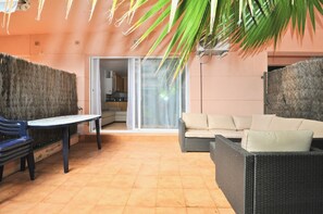 Eine Terrasse mit einem Korbsessel, einem blauen Stuhl und einem Tisch.