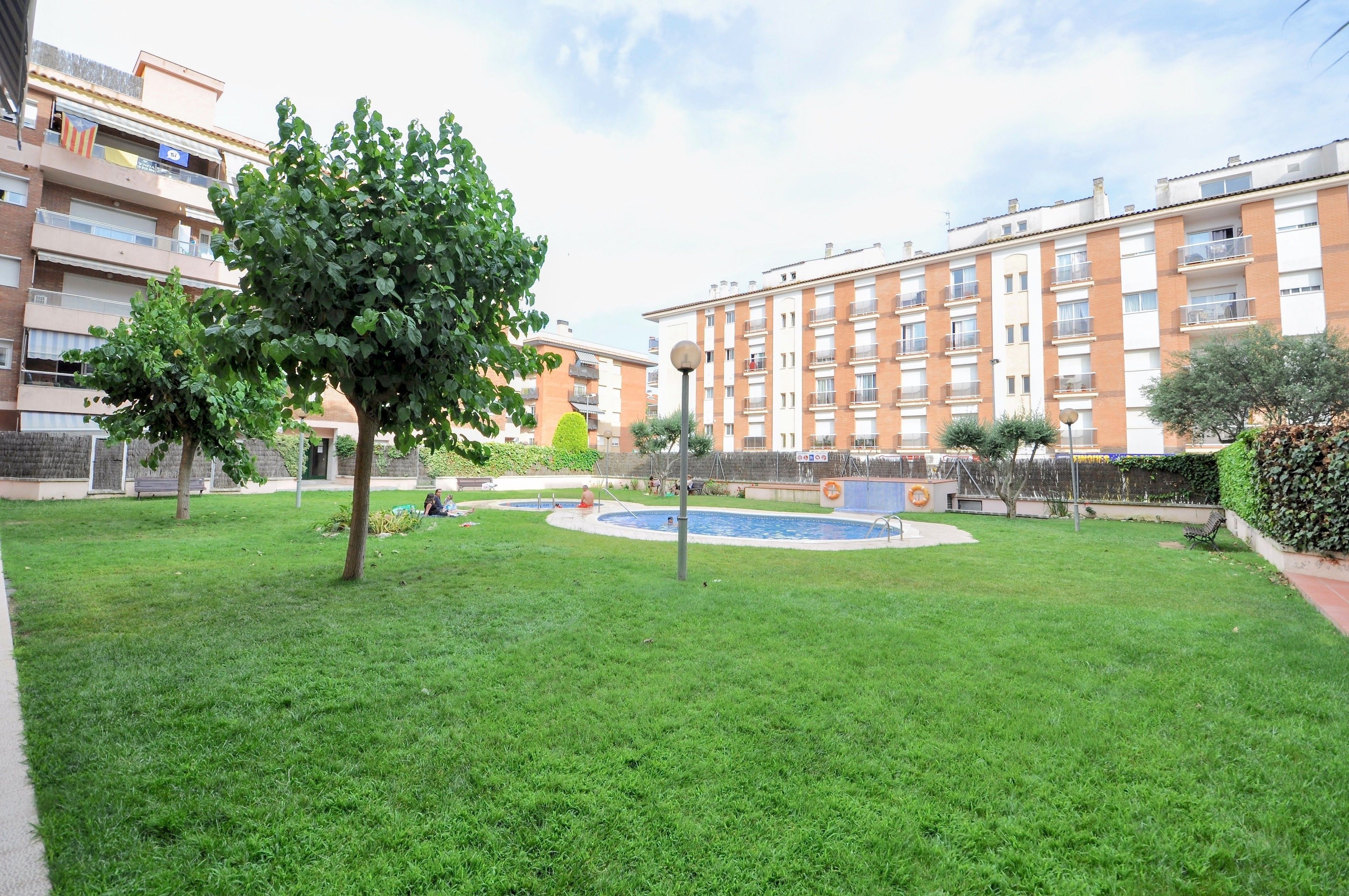 Een binnentuin met een zwembad, omringd door appartementencomplexen.