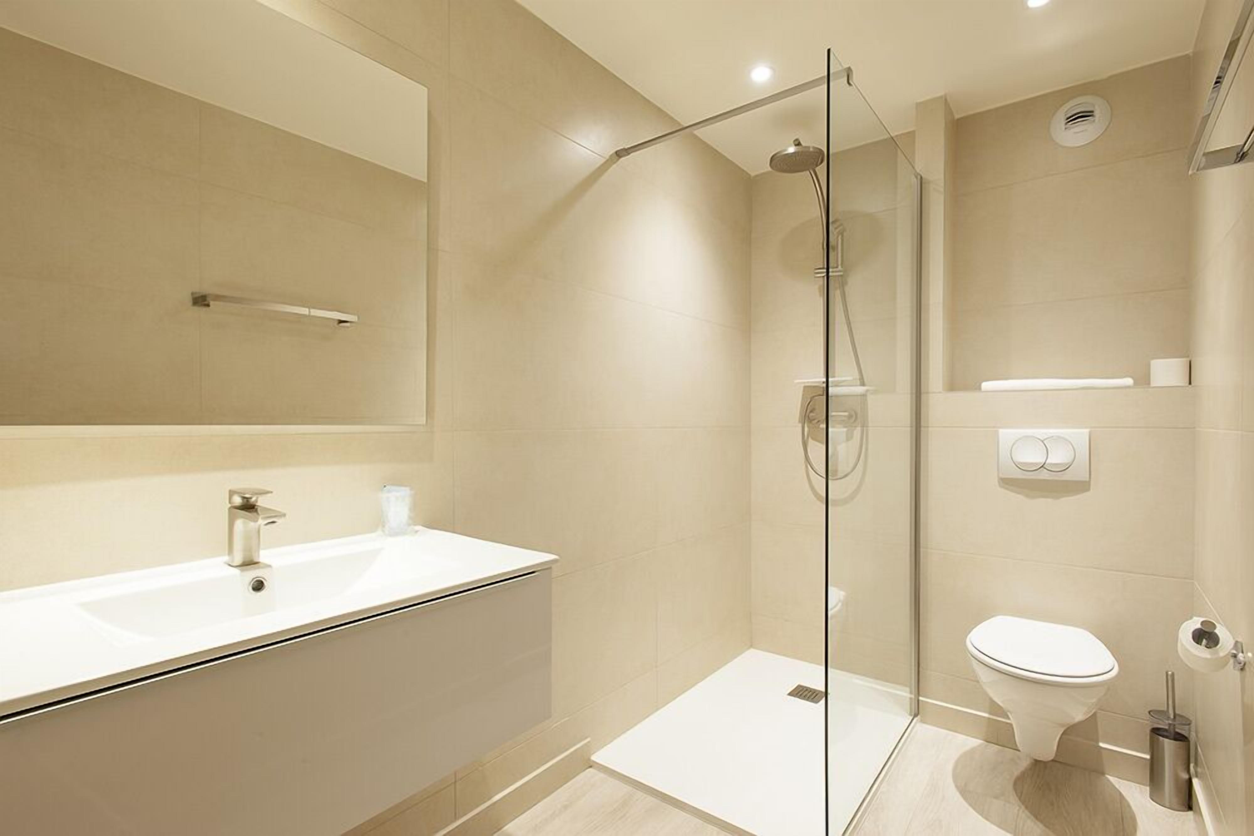 A modern bathroom with a glass-enclosed shower, a white sink, and a toilet.