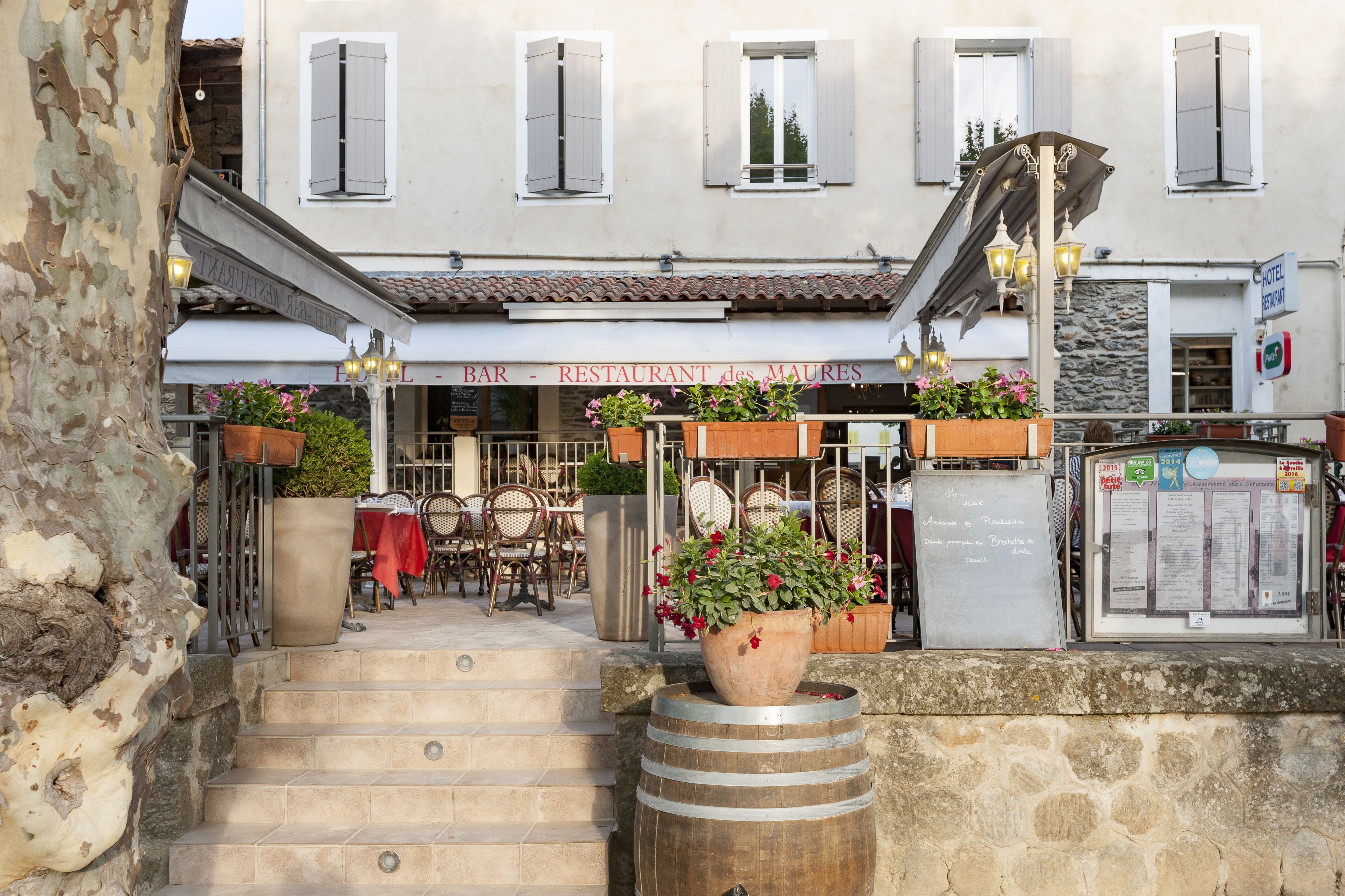 A restaurant with outdoor seating, stone steps, and potted plants.