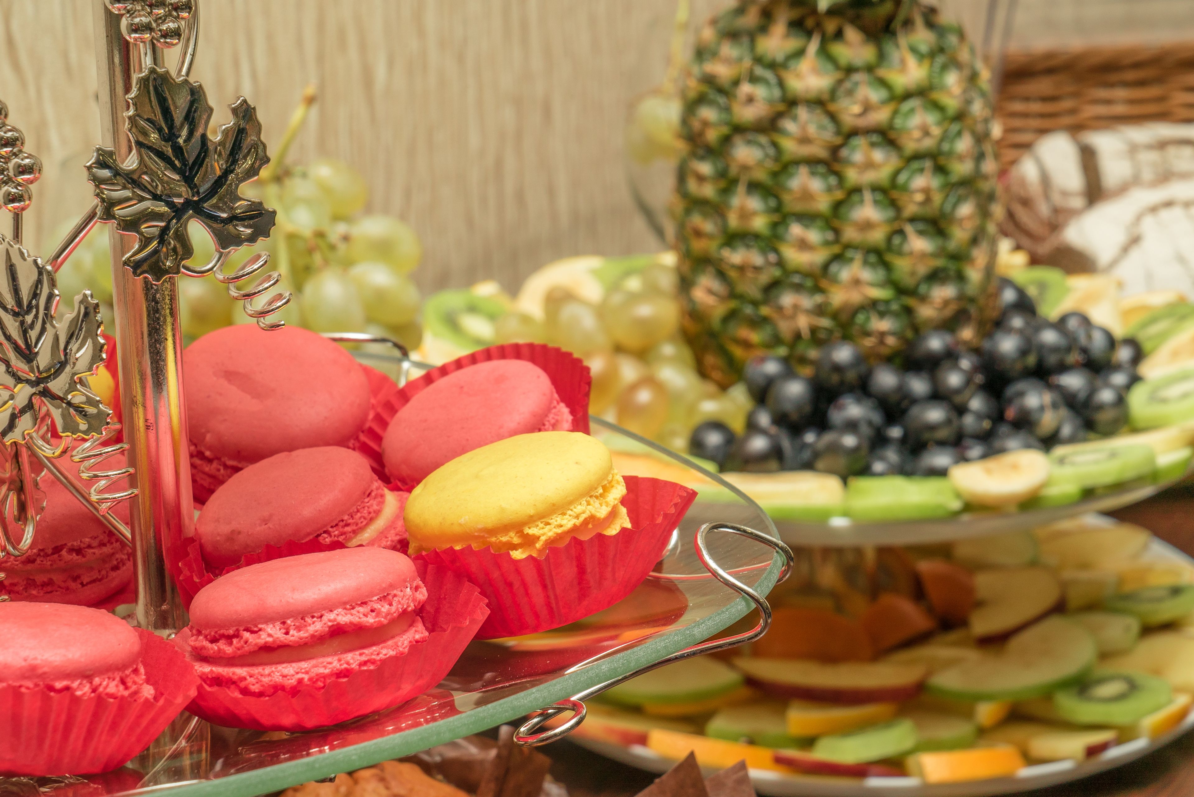 A buffet with macarons, fruits, and a decorative pineapple centerpiece.