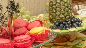 A buffet with macarons, fruits, and a decorative pineapple centerpiece.