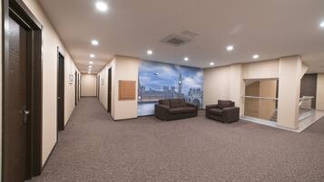 A hallway with a carpeted floor, a mural of a city skyline, and a staircase leading to an upper level.