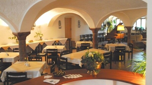 Un comedor interior con mesas y sillas, techos abovedados y una lámpara.