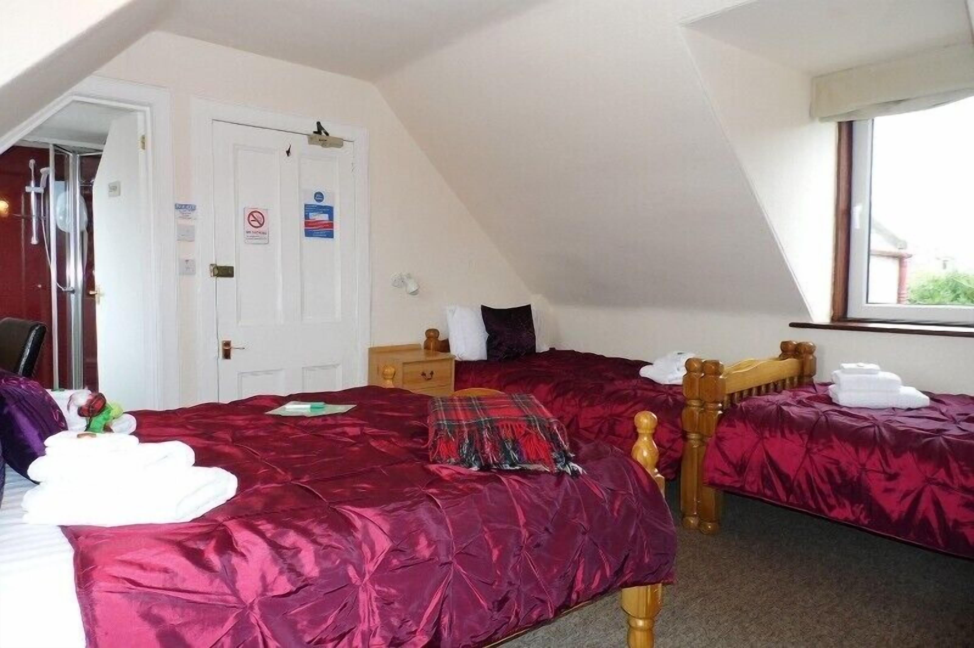 A room with two beds, a wooden headboard, a window, and a door with a sign.