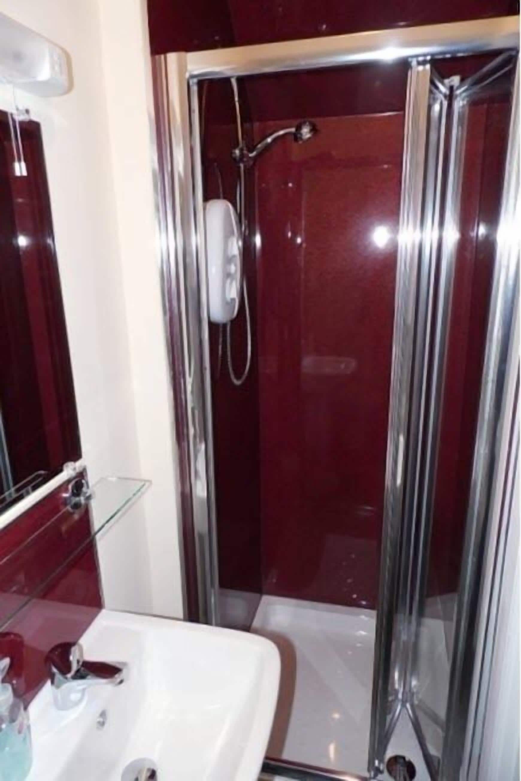Un baño con ducha de vidrio, un lavabo blanco y un espejo.