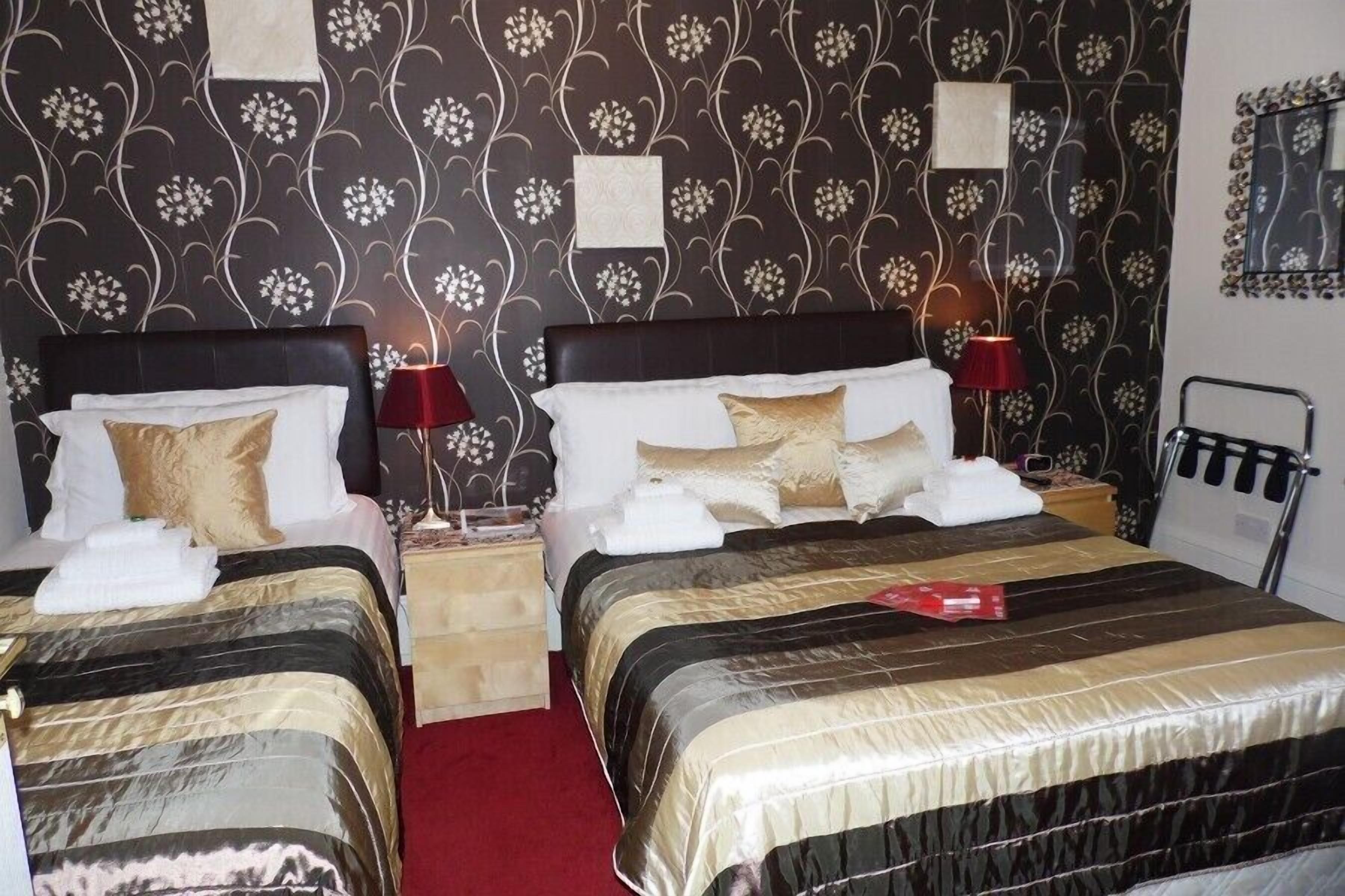 Een hotelkamer met twee bedden, elk met hoofdeind, nachtkastjes, lampen en handdoeken.