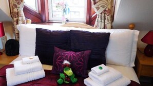 Een hotelkamer met een bed, kussens, een knuffel en handdoeken.