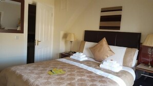 Een hotelkamer met een groot bed, een hoofdeinde, een nachtkastje, een lamp en een spiegel.