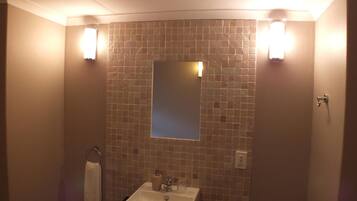 Un baño con un lavabo blanco, un espejo y dos luces fijadas en la pared.