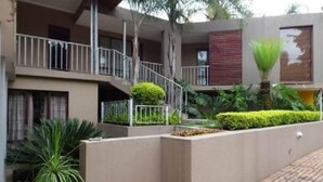 Un edificio de varios pisos con un patio central, que incluye una escalera, barandillas y diversas plantas.