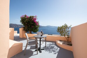 Une terrasse avec une table et des chaises, une bouteille de vin et une vue sur la mer.