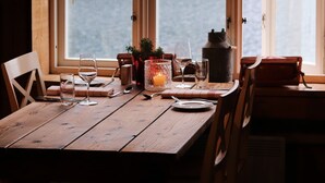 Et træspisebord med stole, et stearinlys og havudsigt gennem store vinduer.