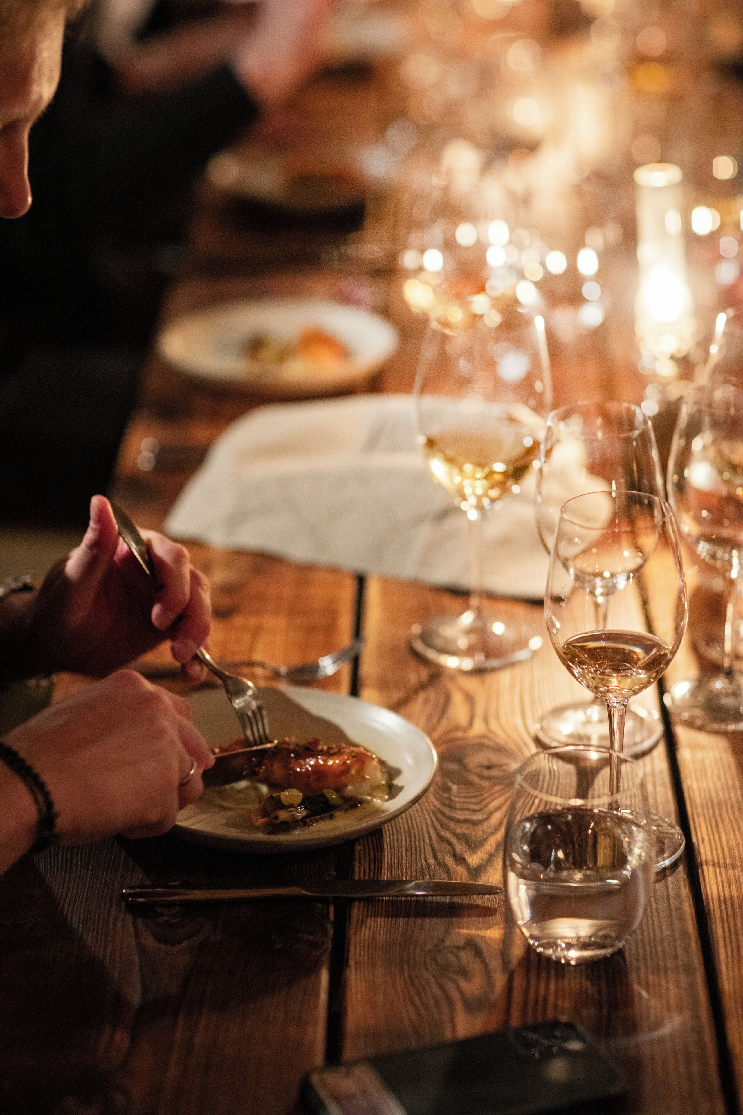 A wooden table with wine glasses and plates, suggesting a dining setting.