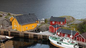 A harbor with a yellow building, a red building, and a boat docked at the pier.