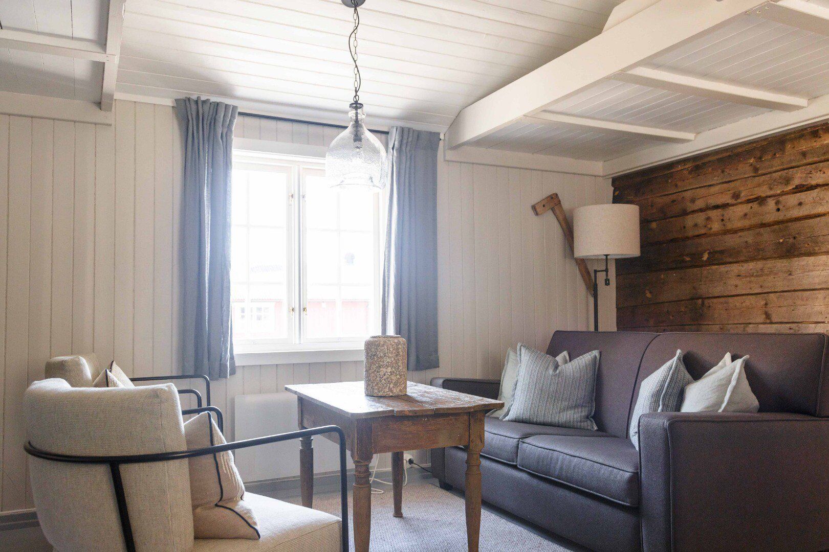 A cozy living room with a sofa, armchair, and a table with a lamp.