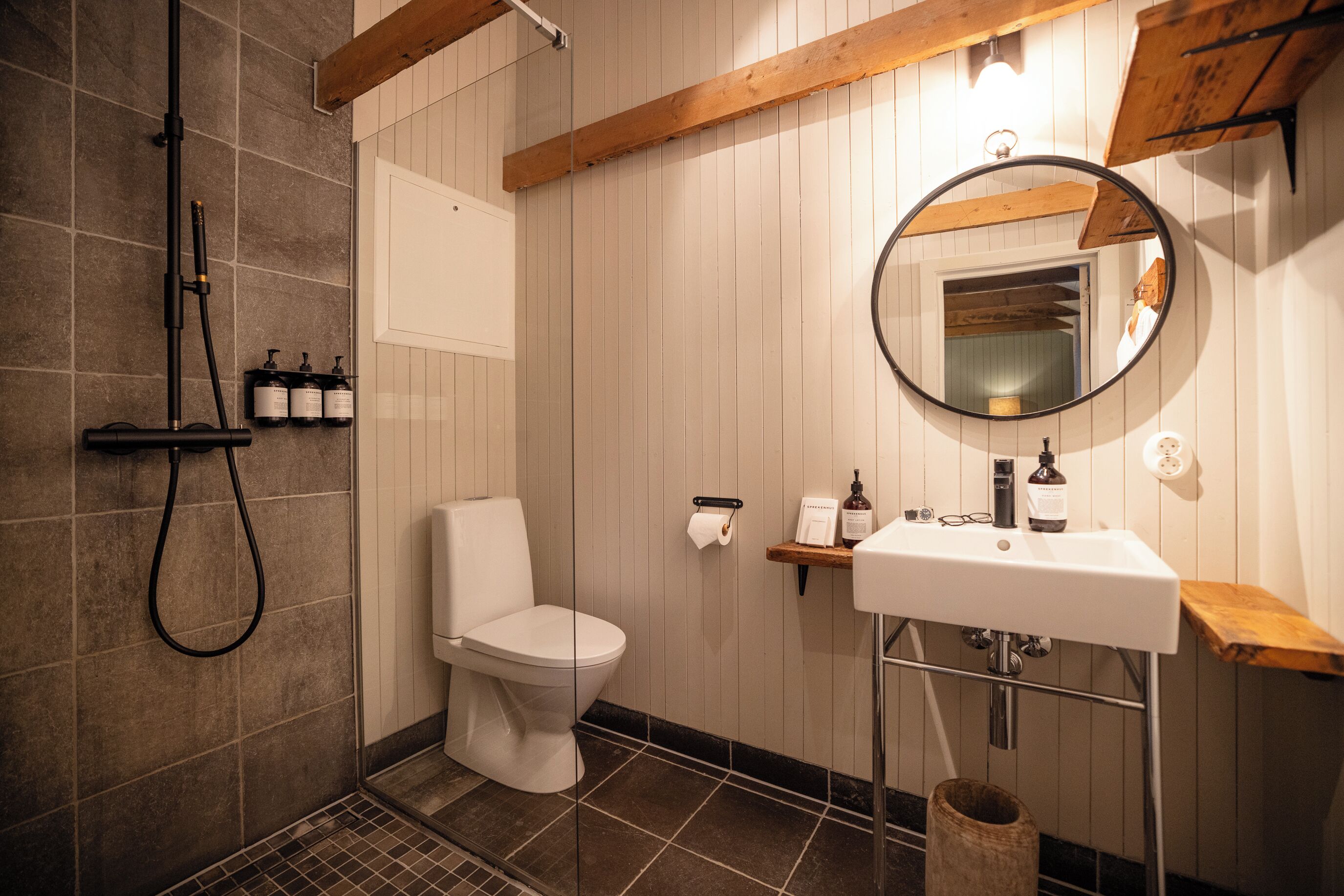 Un baño con ducha, inodoro, lavamanos y espejo.