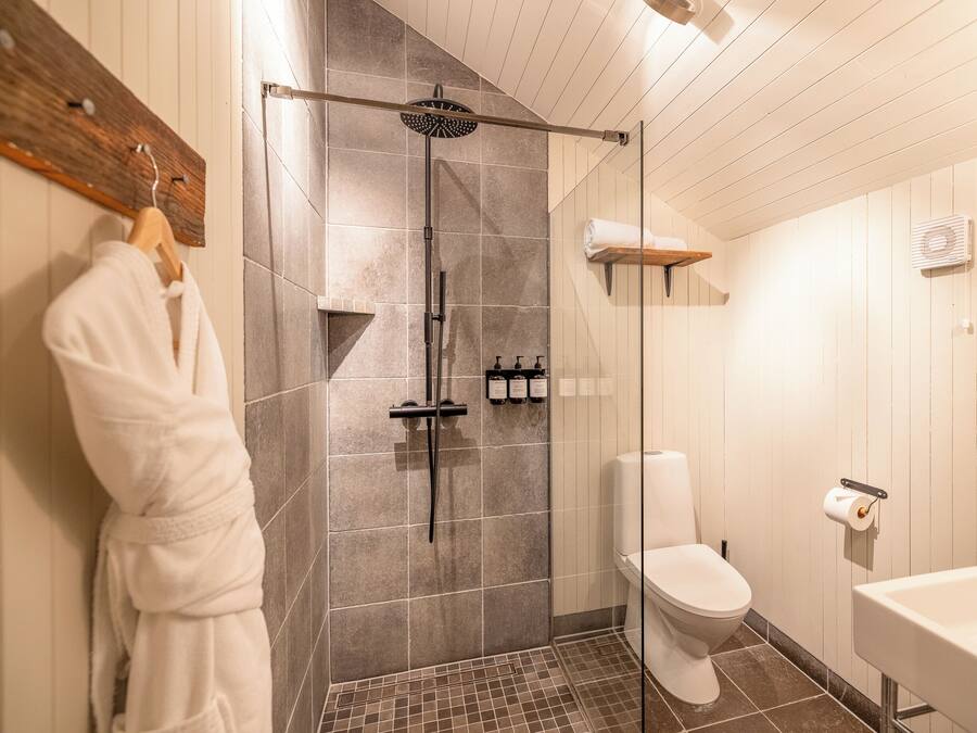 Et badeværelse med bruser, toilet og vask.
