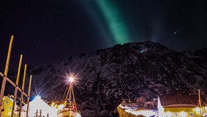 A harbor with boats, a lighthouse, and a mountain in the background. - Nusfjord Village & Resort (Flakstad)