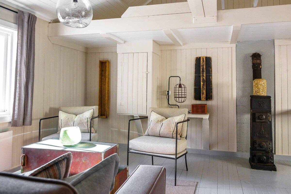Una habitación acogedora con dos sillones, una mesita, una radio antigua y un estante decorativo.