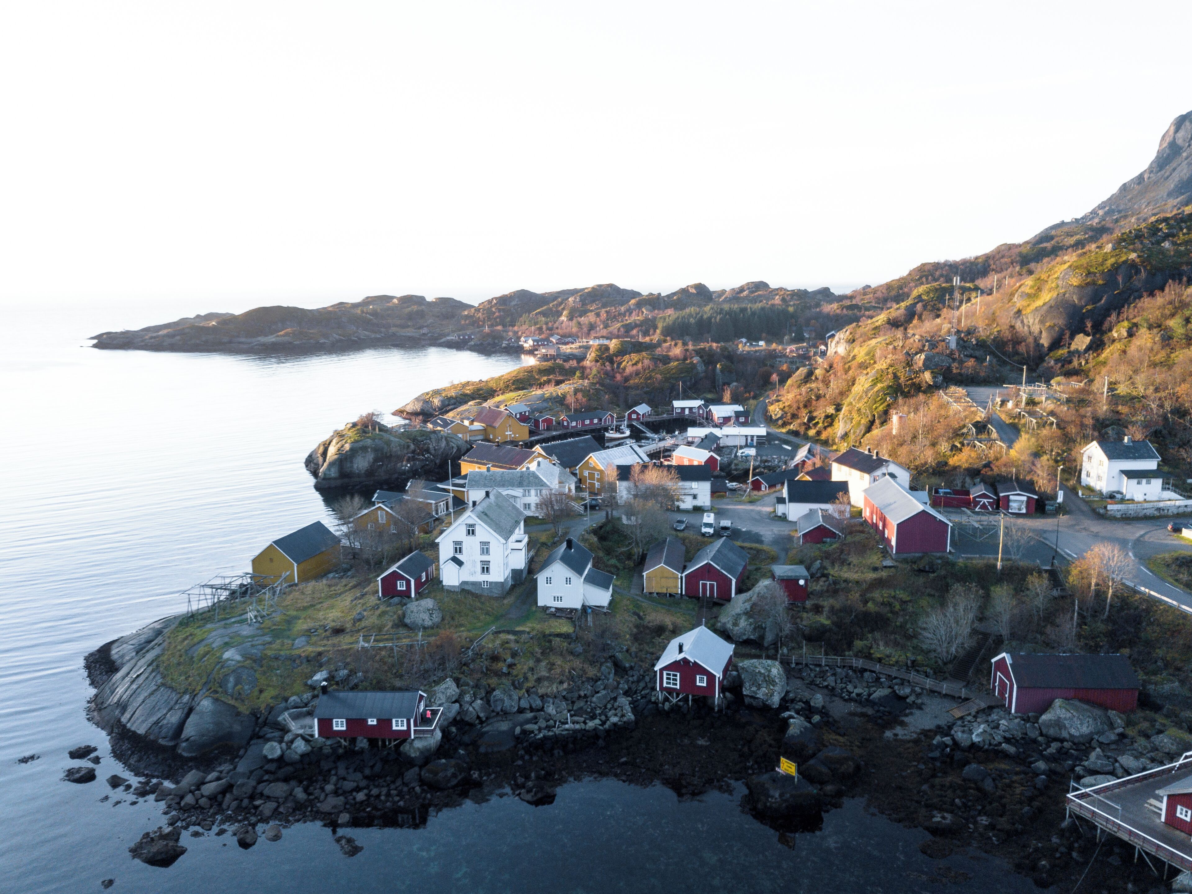 A coastal village with houses, a dock, and a road leading to a bridge.