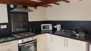 A compact kitchen with a built-in oven, a microwave, a coffee maker, and a sink. - Holly Cottage (Skegness)