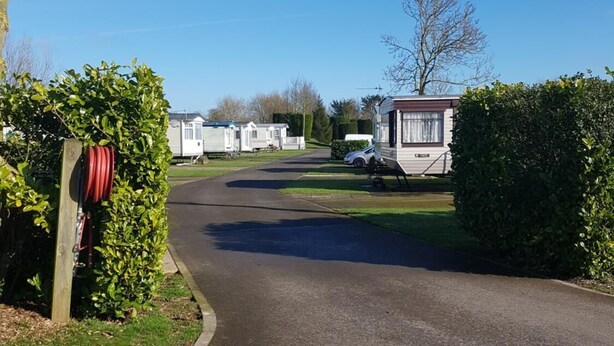 A residential area with a paved road leading to a row of mobile homes. - Holly Cottage (Skegness)