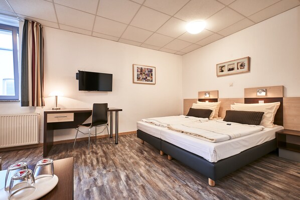 Habitación de hotel moderna con cama, escritorio, silla y televisor.