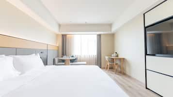 Una habitación de hotel con una cama grande, un escritorio, una silla y un televisor.