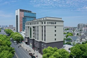 Hotel com fachada moderna, vista clara da rua e área de estacionamento.