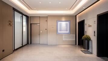 Un pasillo moderno con una puerta de vidrio, una obra de arte enmarcada en la pared y una planta en maceta.