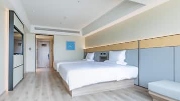 A modern hotel room with a large bed, a bedside table, a built-in bench, and a view of the hallway.