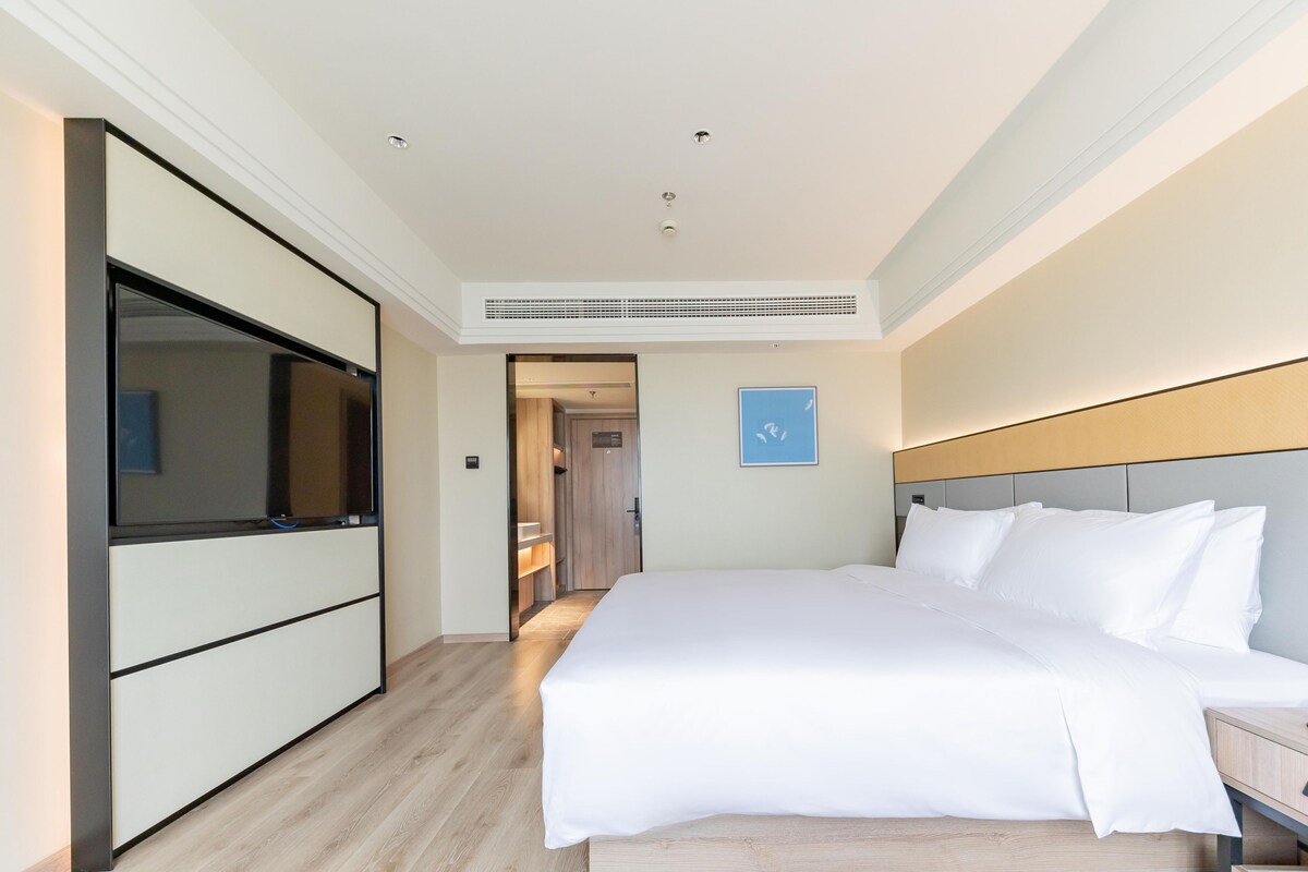 Quarto de hotel com cama, mesa de cabeceira e guarda-roupa.