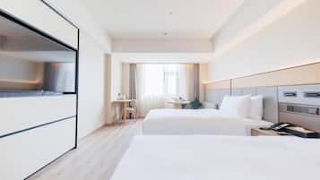 A hotel room with two beds, a desk, a chair, a TV, and a phone.