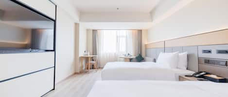 Habitación de hotel con dos camas, un escritorio, una silla, un televisor y un teléfono.