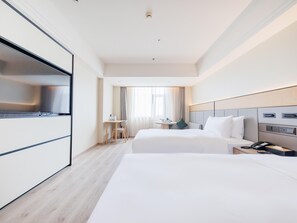 Habitación de hotel con dos camas, un escritorio, una silla, un televisor y un teléfono.