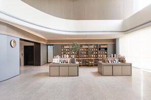 Un interior moderno con una zona de estar central, una estantería y un cartel que dice '2040 BOOKSTORE'.