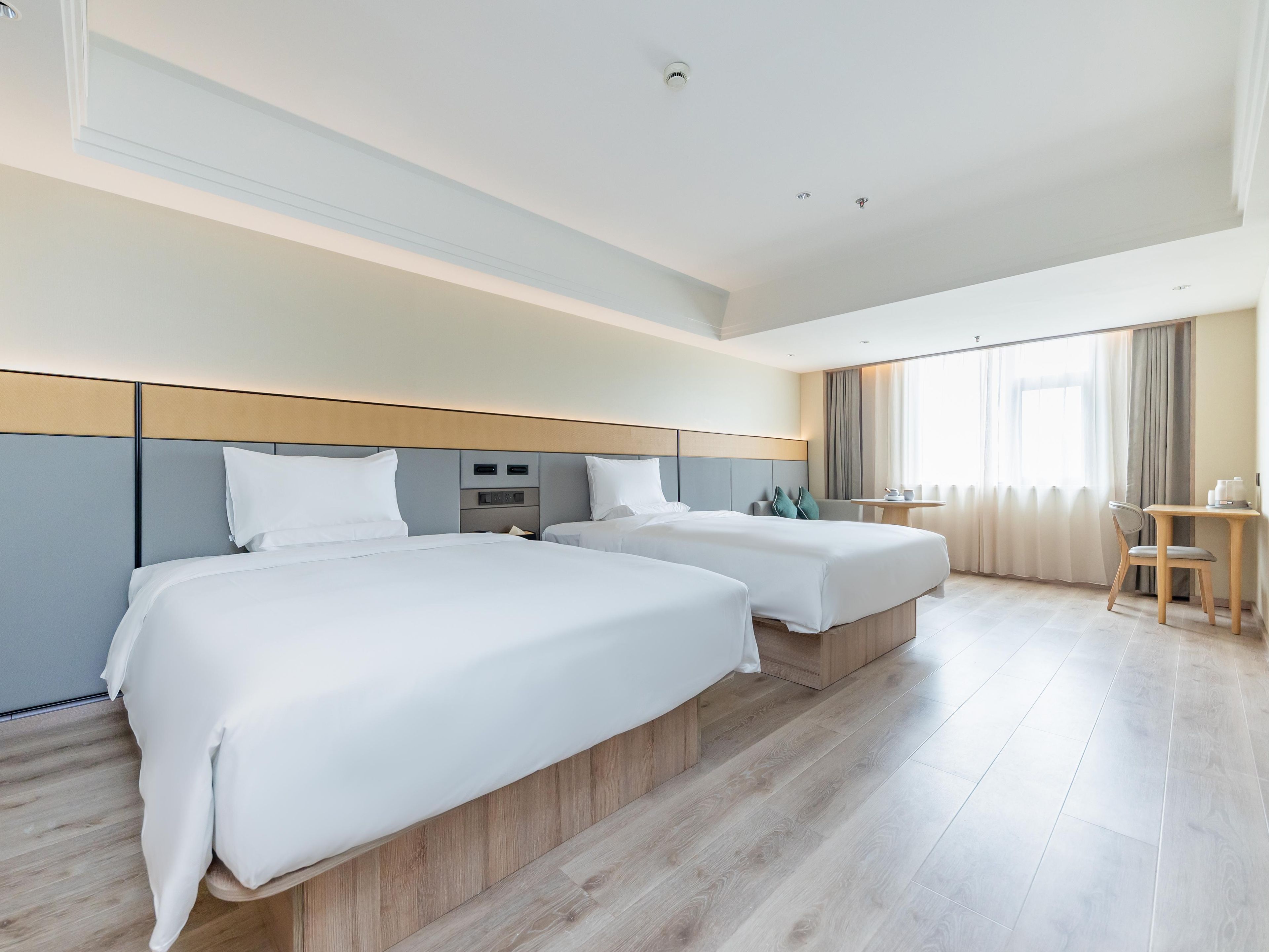 A hotel room with two beds, a desk, and a chair.