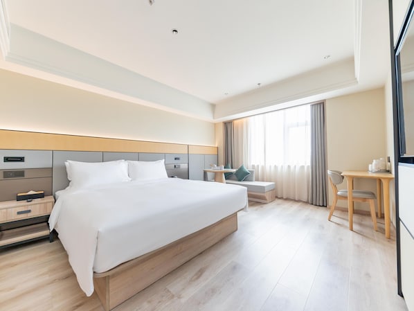 Une chambre d’hôtel avec un grand lit, une table de chevet, un bureau, une chaise et un téléviseur.